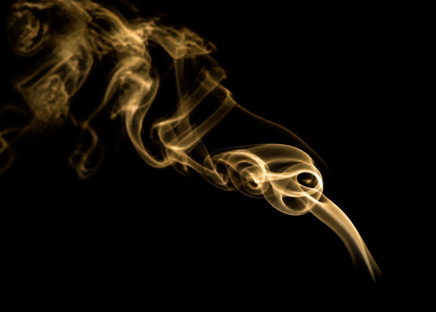 Cigar smoke curling against a black background